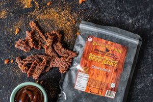 Photo of Smokey BBQ flavored Brisket Beef Jerky with seasonings and BBQ dip on the side.